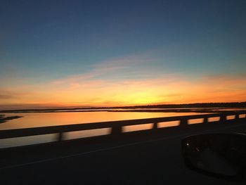 Silhouette bridge over river against sky during sunset