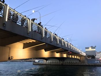 Low angle view of bridge in istanbul over bosforo river against clear sky crowded of fisherman