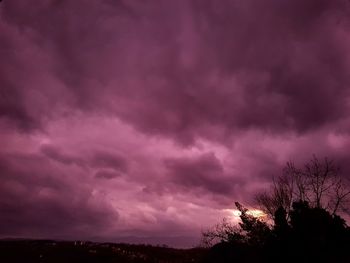 Low angle view of silhouette trees against dramatic sky