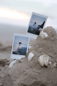 Close-up of photographs on sand at beach