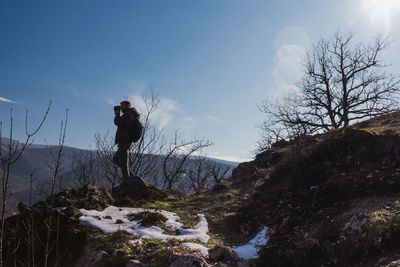 Man standing on rock against sky