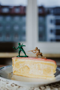 Two toy soldiers fighting on the top of a piece of cake about having a dessert or not - close up 