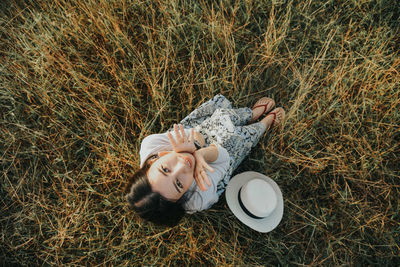 High angle portrait of beautiful woman sitting on grassy field
