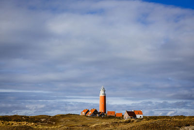 Lighthouse on field against sky