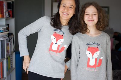 Portrait of a smiling young woman - mother and daughter with the same fox on their t-shirts