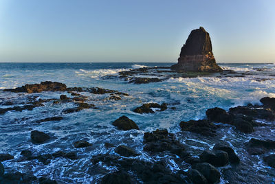 Scenic view of rocks in sea against sky