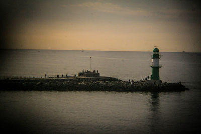 Lighthouse by sea against sky