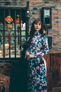 Portrait of young woman standing against built structure