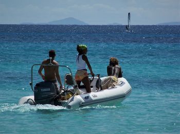 People on boat in sea against sky