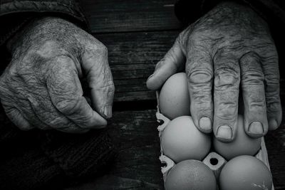 Cropped hand of man touching eggs on table