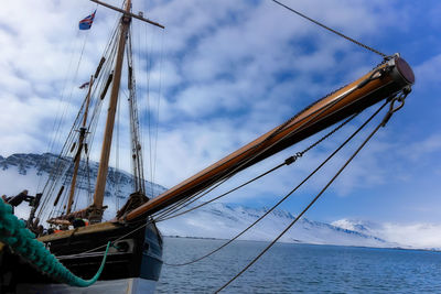 Sailboats moored at harbor against cloudy sky