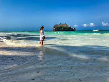 Full length of woman standing on beach against sky