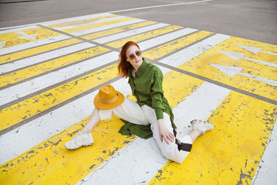 Portrait of a smiling young woman sitting on yellow umbrella