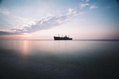 Silhouette boat in sea against sky during sunset