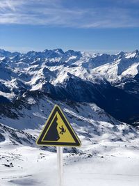 Road sign against snowcapped mountains during winter