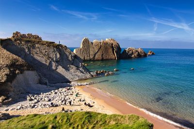 Panoramic view of rocks on beach against blue sky