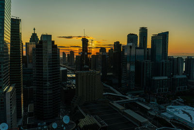 Modern buildings in city against sky during sunset