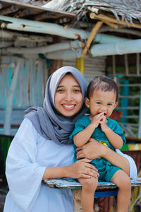 Portrait of happy mother and her son sitting outdoors