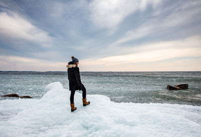 Rear view of man standing on sea shore against sky