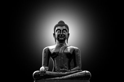 Statue of buddha against black background