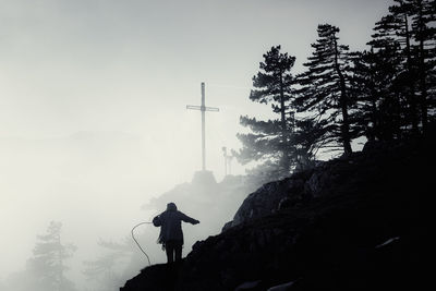 Low angle view of silhouette man standing on mountain against sky