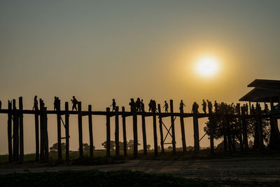 Silhouette people on land against clear sky during sunset