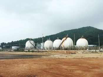 Storage tanks at factory against sky