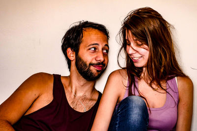 Portrait of happy young couple against wall