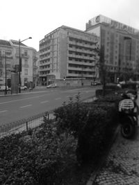 Road by buildings against sky in city