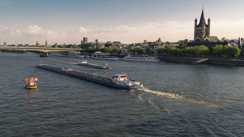 Sailboats in river with city in background