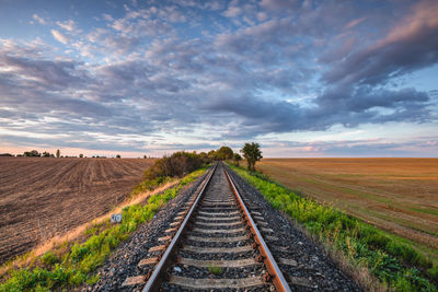 Railroad tracks on field against sky