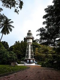 Lighthouse amidst trees and building against sky