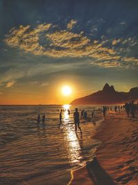 Silhouette people on beach against sky during sunset