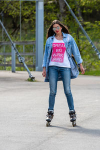 Full length portrait of young woman wearing sunglasses standing outdoors