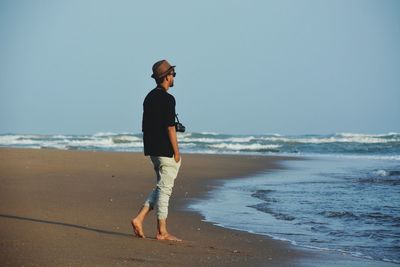 Full length of man standing at beach against clear sky