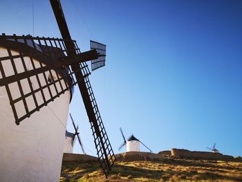 Low angle view of traditional windmill against clear blue sky