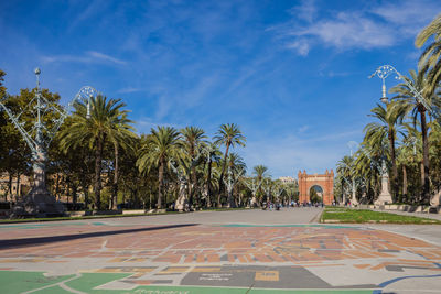 Road by palm trees against blue sky