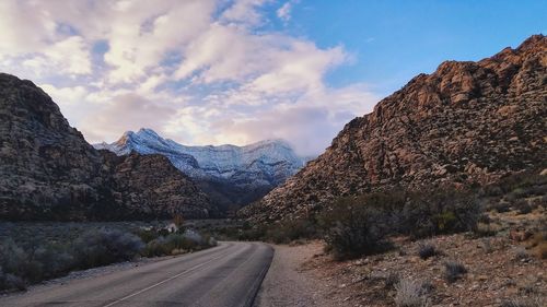 Road by mountains against sky during winter