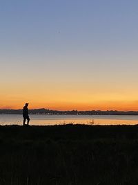 Silhouette man standing on beach against sky during sunset