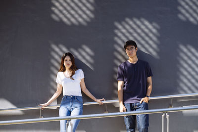 Portrait of a young woman standing against railing