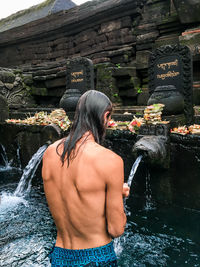 Shirtless man standing in water at temple