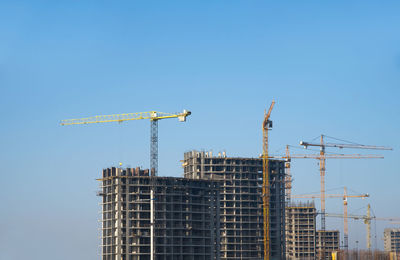 Low angle view of crane against clear blue sky