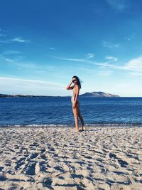 Woman standing at beach against sky