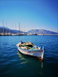 Sailboat moored on sea against clear blue sky