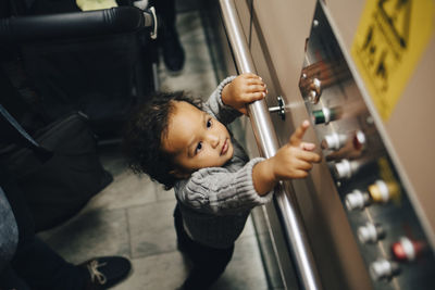 High angle view of girl pressing button while standing by door