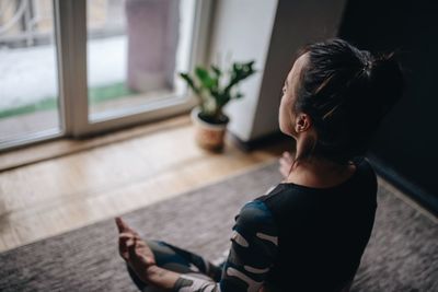 Woman doing yoga on rug in apartment