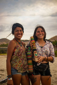 Portrait of smiling young woman standing against sky