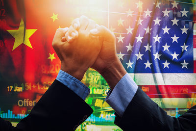 Business colleagues holding hands against chinese and american flag