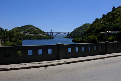 Bridge by road against clear blue sky