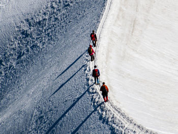 High angle view of people hiking on snow covered mountain